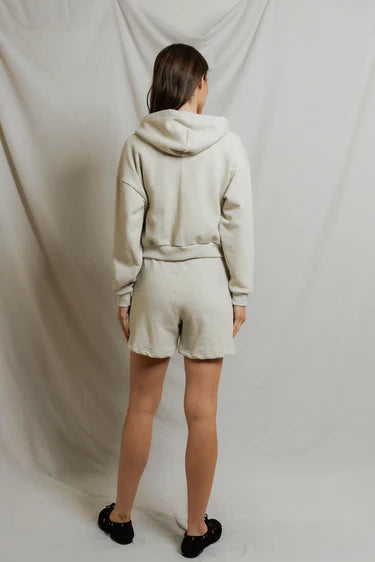 model wearing a zip up hoodie and lounge shorts in the color oatmeal, back view