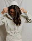 model wearing a zip up hoodie and lounge shorts in the color oatmeal