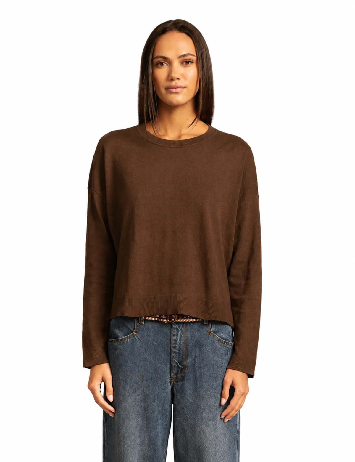 model wearing a brown sweater with jeans on a white background 