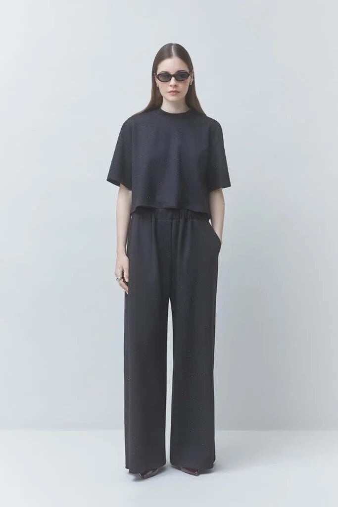 model wearing a black tshirt with black pants on a black background 