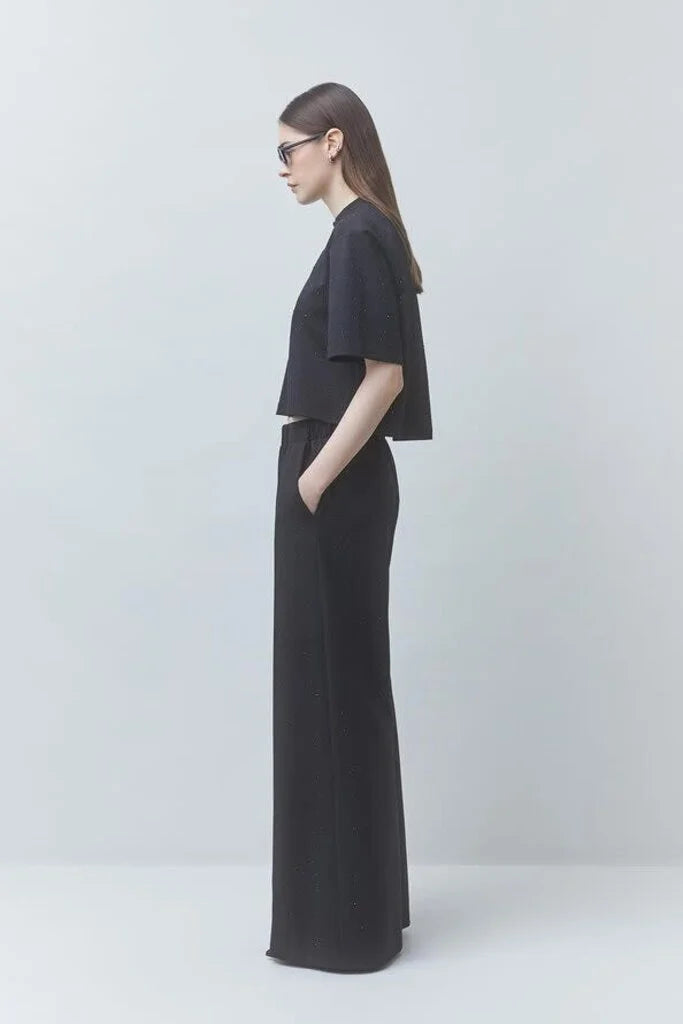 model wearing a black tshirt with black pants on a black background, side