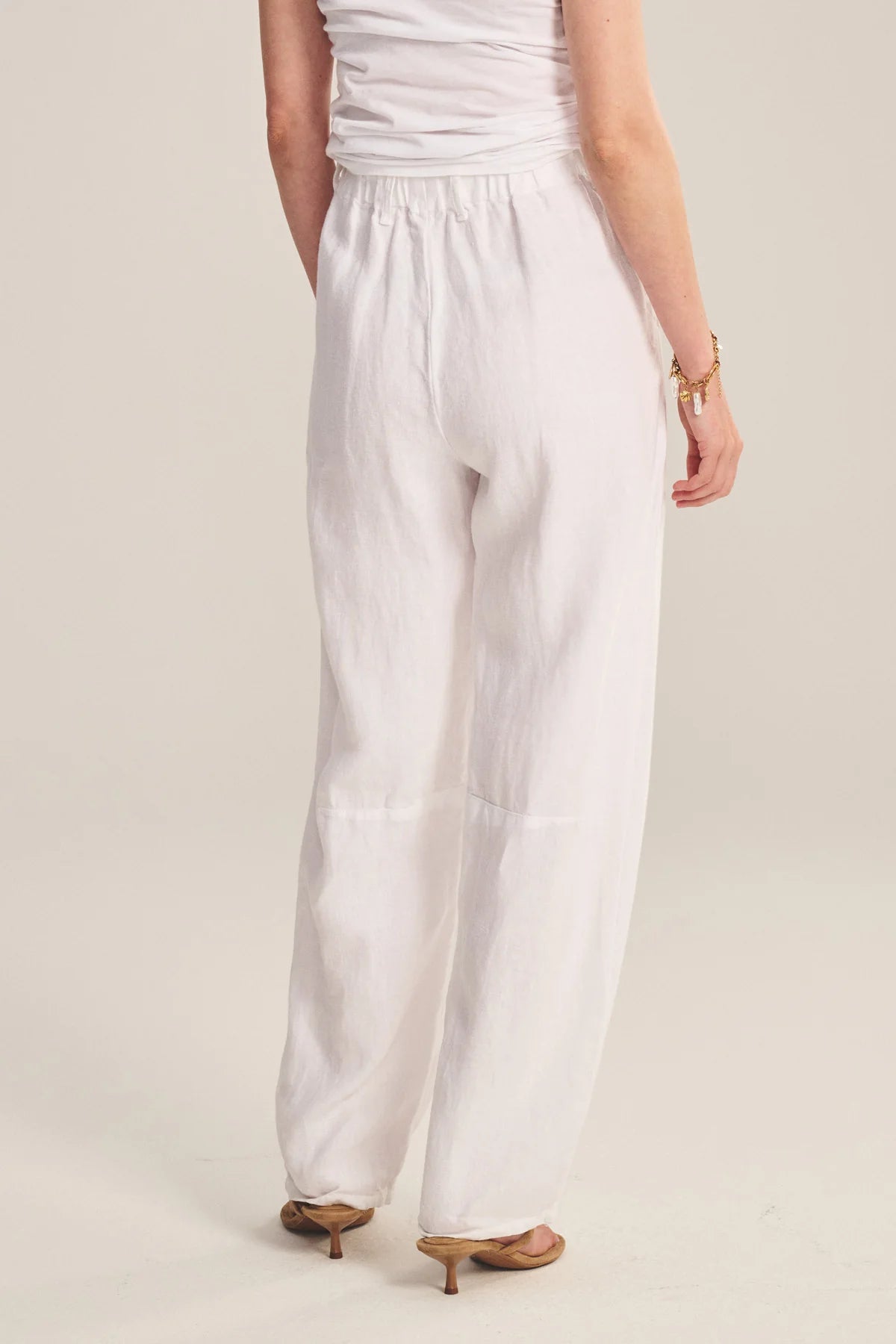 Person wearing a white outfit with wide-leg pants on a plain background
