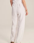 Person wearing a white outfit with wide-leg pants on a plain background
