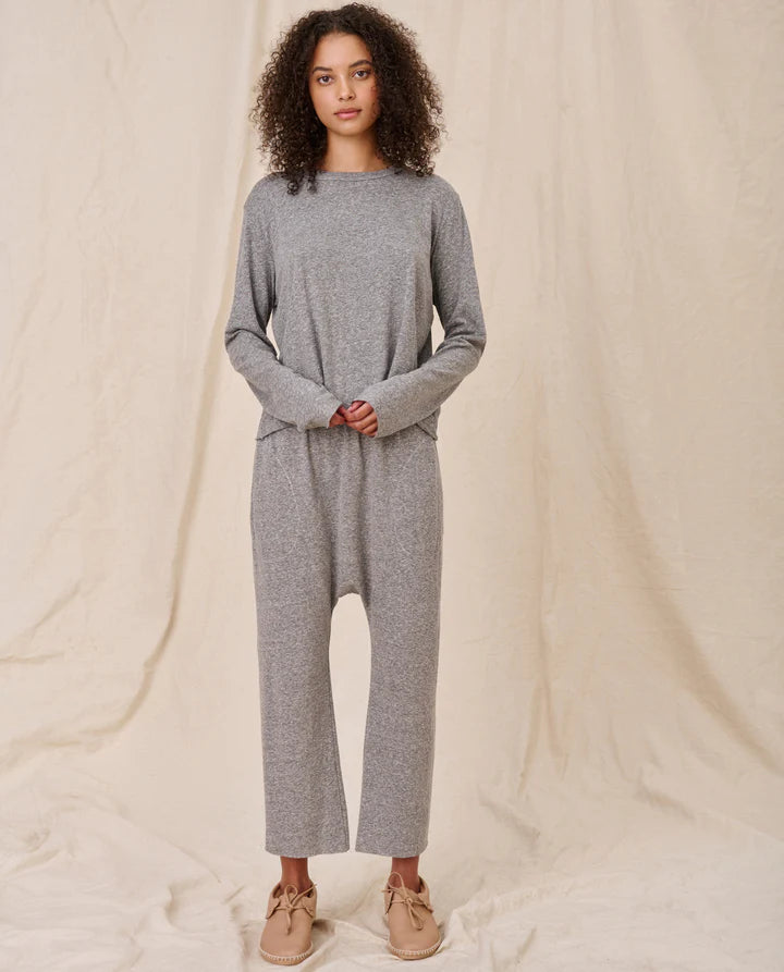Woman wearing a gray lounge set against a beige background, full body