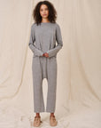 Woman wearing a gray lounge set against a beige background, full body