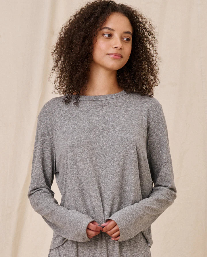 Woman wearing a gray long-sleeve top against a beige background, front