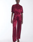 model wearing a wine colored silk short sleeve top and matching pant on a white background 