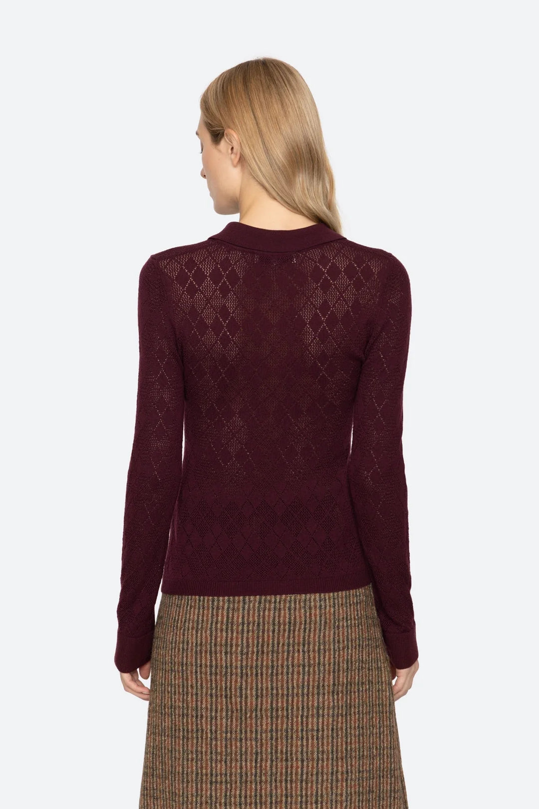 Woman wearing a burgundy sweater with a patterned design on a white background