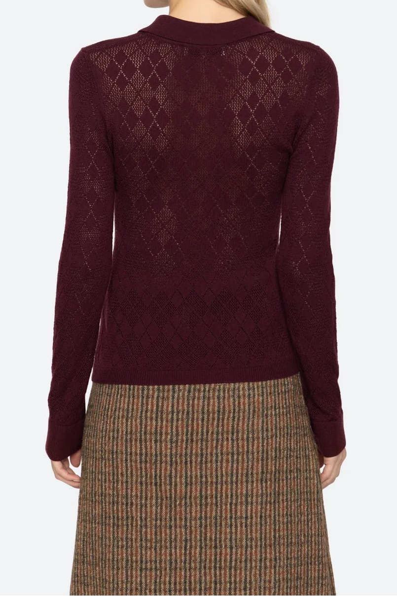 Woman wearing a burgundy sweater with a patterned design on a white background