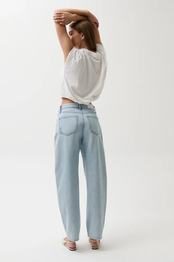 Person wearing a white top and light blue jeans on a plain background