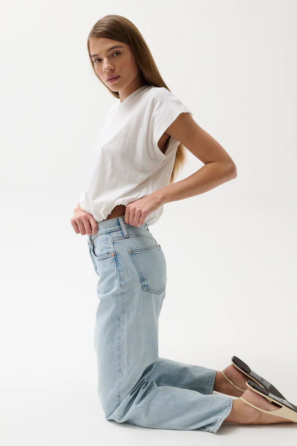 Woman wearing a white top and light blue jeans on a white background
