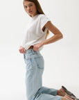 Woman wearing a white top and light blue jeans on a white background