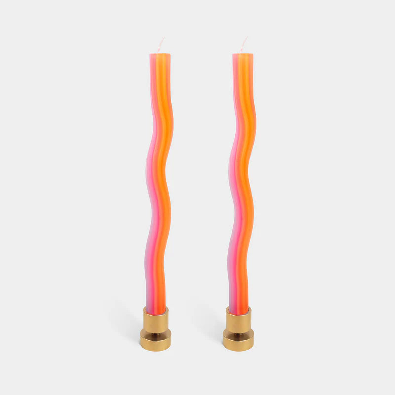 Two wavy candles with pink and orange colors and gold bases on a white background