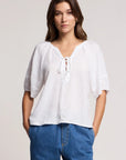 Woman wearing a white blouse and blue jeans against a plain background