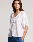 Woman wearing a white blouse with a plain background