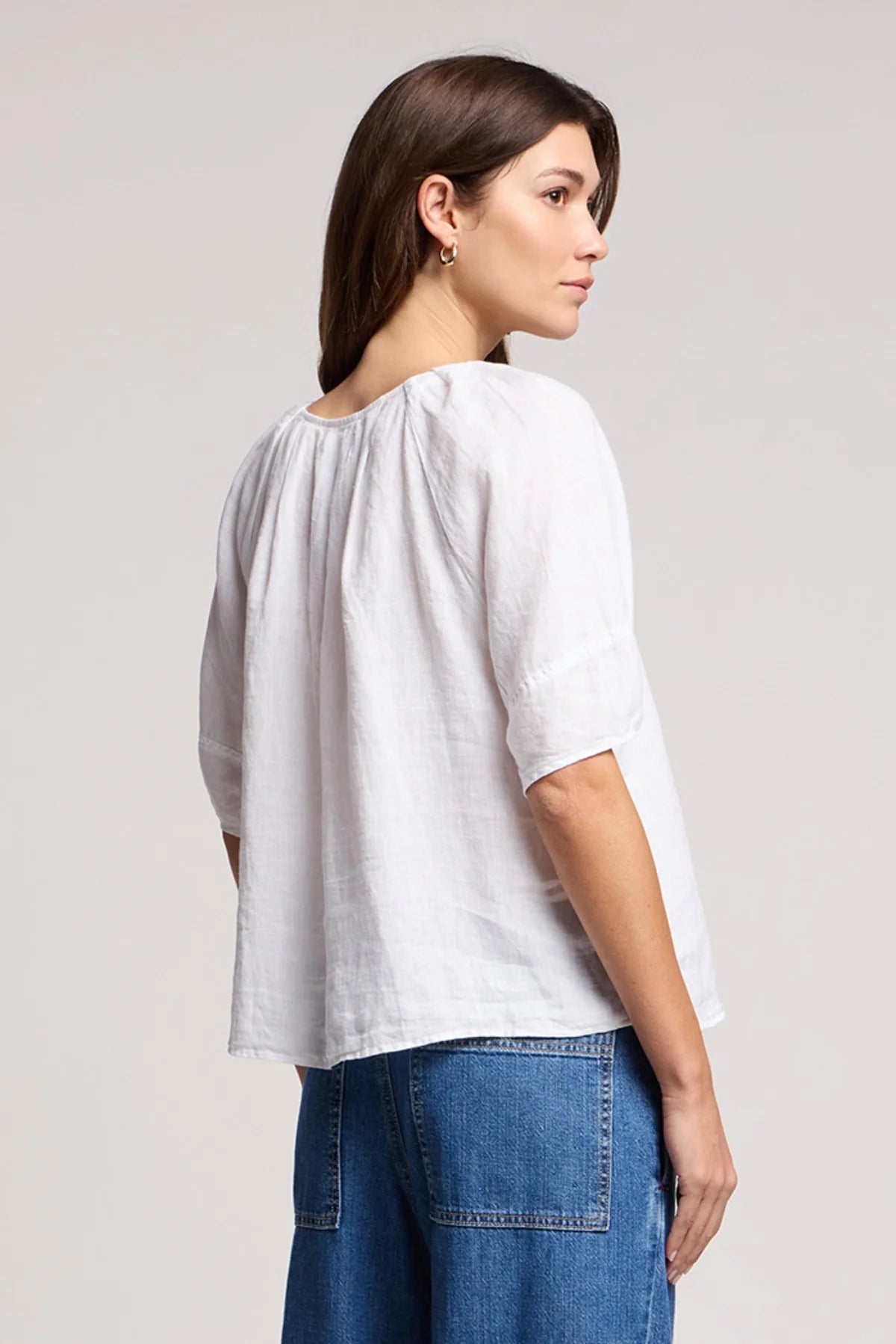 Woman wearing a white blouse and blue jeans on a plain background