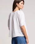 Woman wearing a white blouse and blue jeans on a plain background