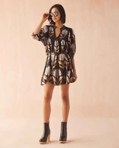 Woman wearing a patterned dress and boots on a beige background