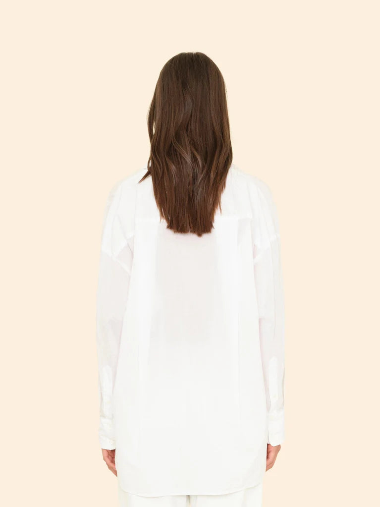 Person wearing a white long-sleeve shirt against a beige background