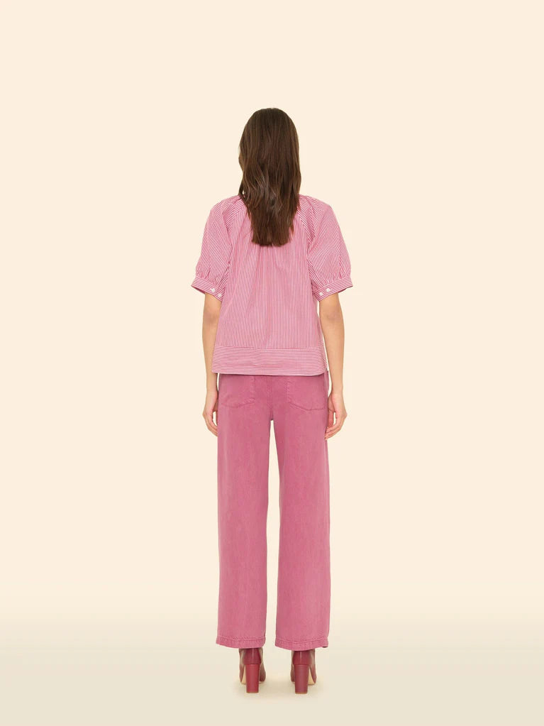 Woman wearing a pink outfit on a beige background, back