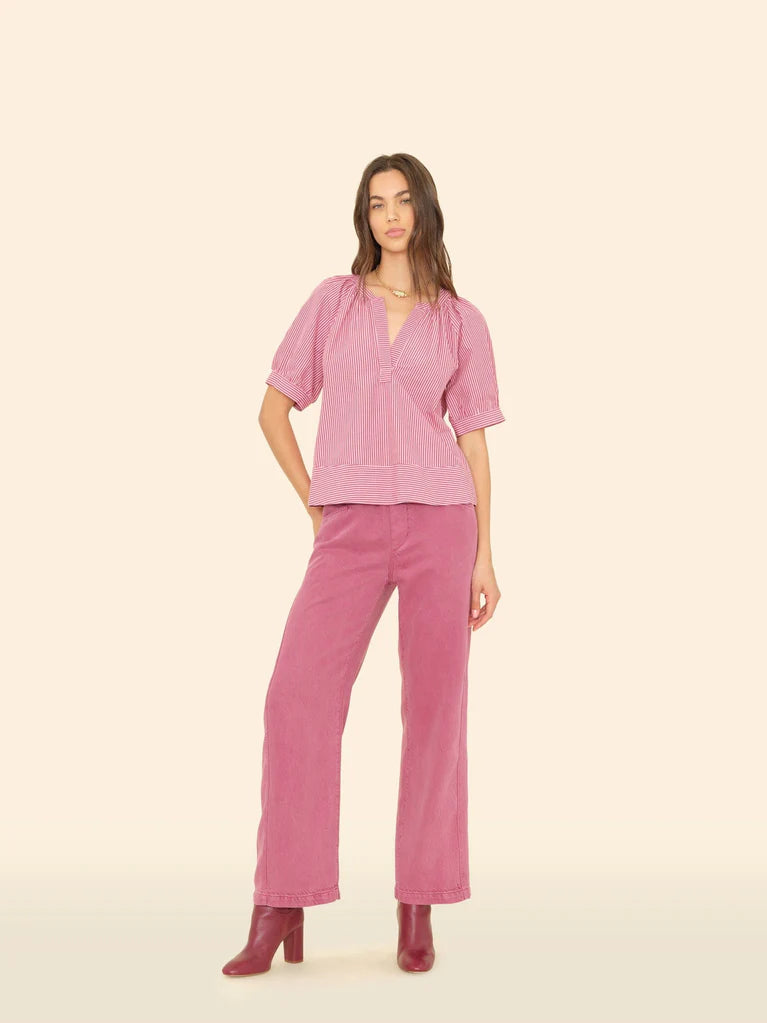 Woman wearing a pink blouse and pants on a beige background