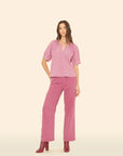 Woman wearing a pink blouse and pants on a beige background