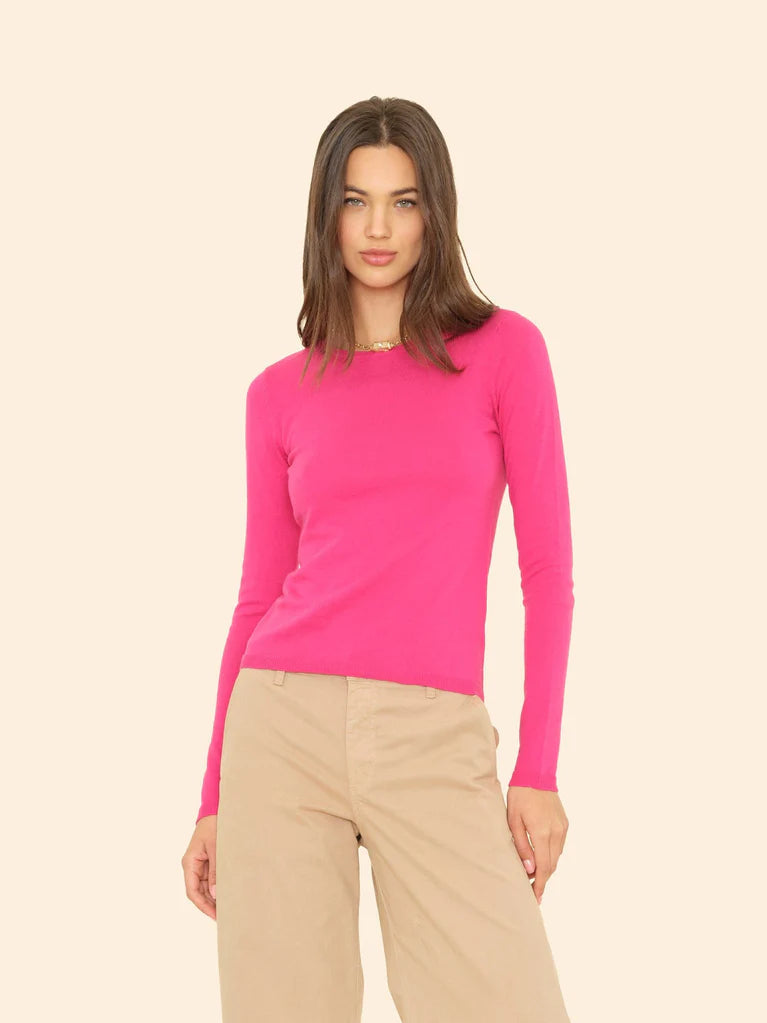 Woman wearing a bright pink sweater and beige pants on a beige background