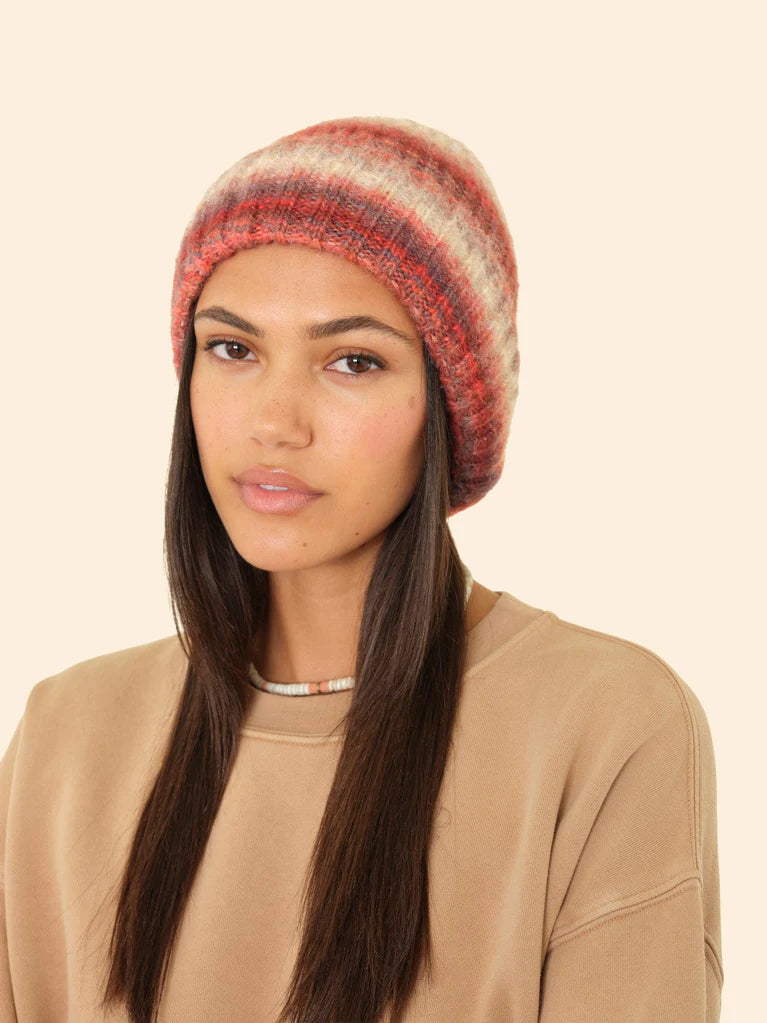 Woman wearing a striped beanie on a beige background