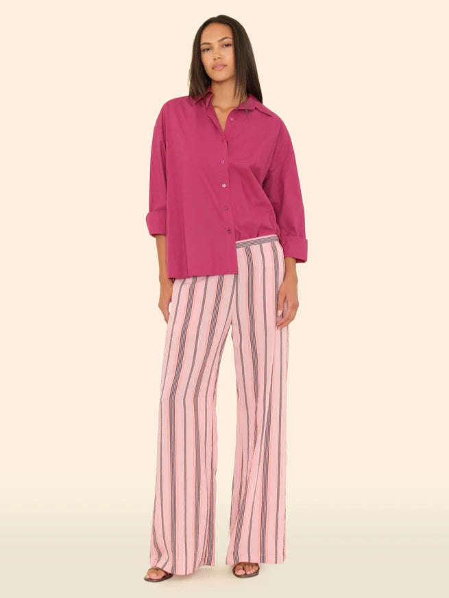 Woman wearing a pink shirt and striped pants on a beige background front view