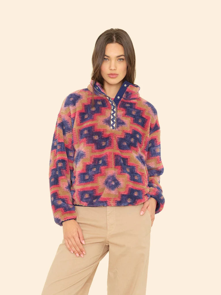 Woman wearing a colorful patterned pullover against a beige background