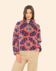 Woman wearing a colorful patterned pullover against a beige background