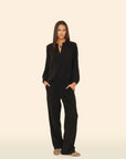Person wearing a black outfit on a beige background