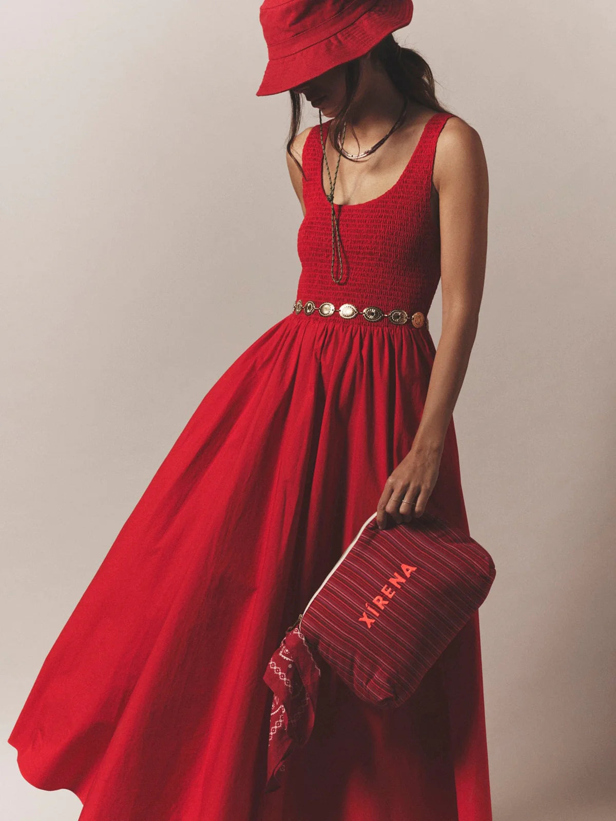 Woman in a red dress holding a matching handbag against a neutral background