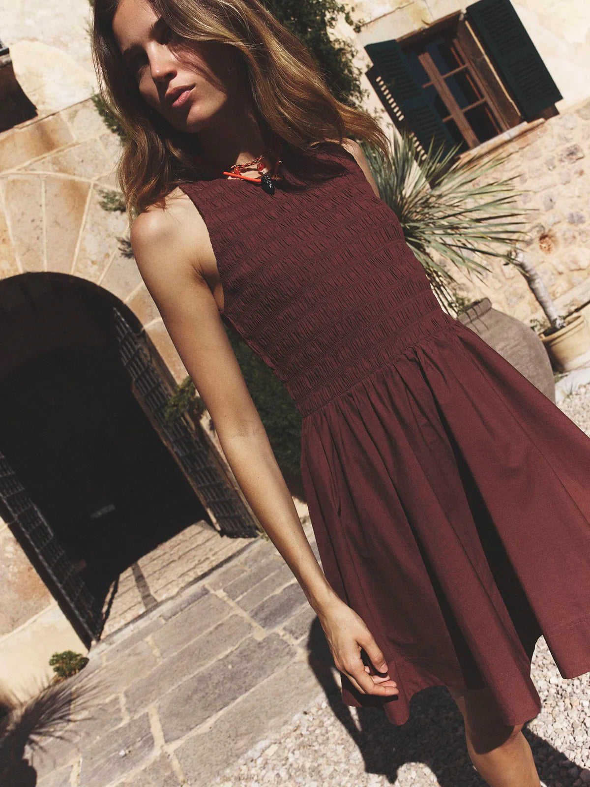 Woman in a Adobe Brown Florie Dress standing outdoors on a stone path.