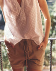 Person wearing a light pink sleeveless top and beige shorts with a blurred natural background