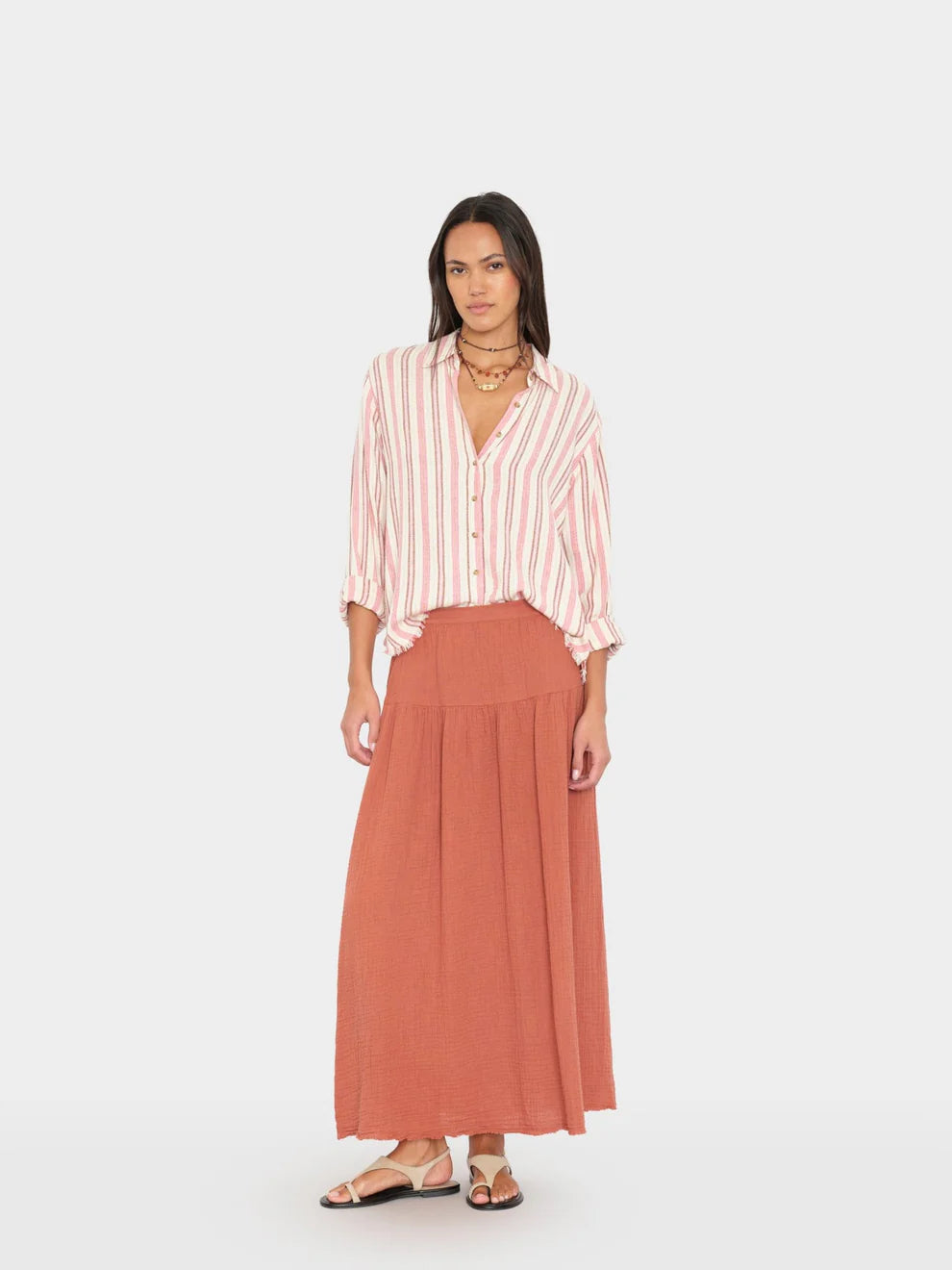 Woman wearing a striped shirt and long rust-colored skirt on a white background