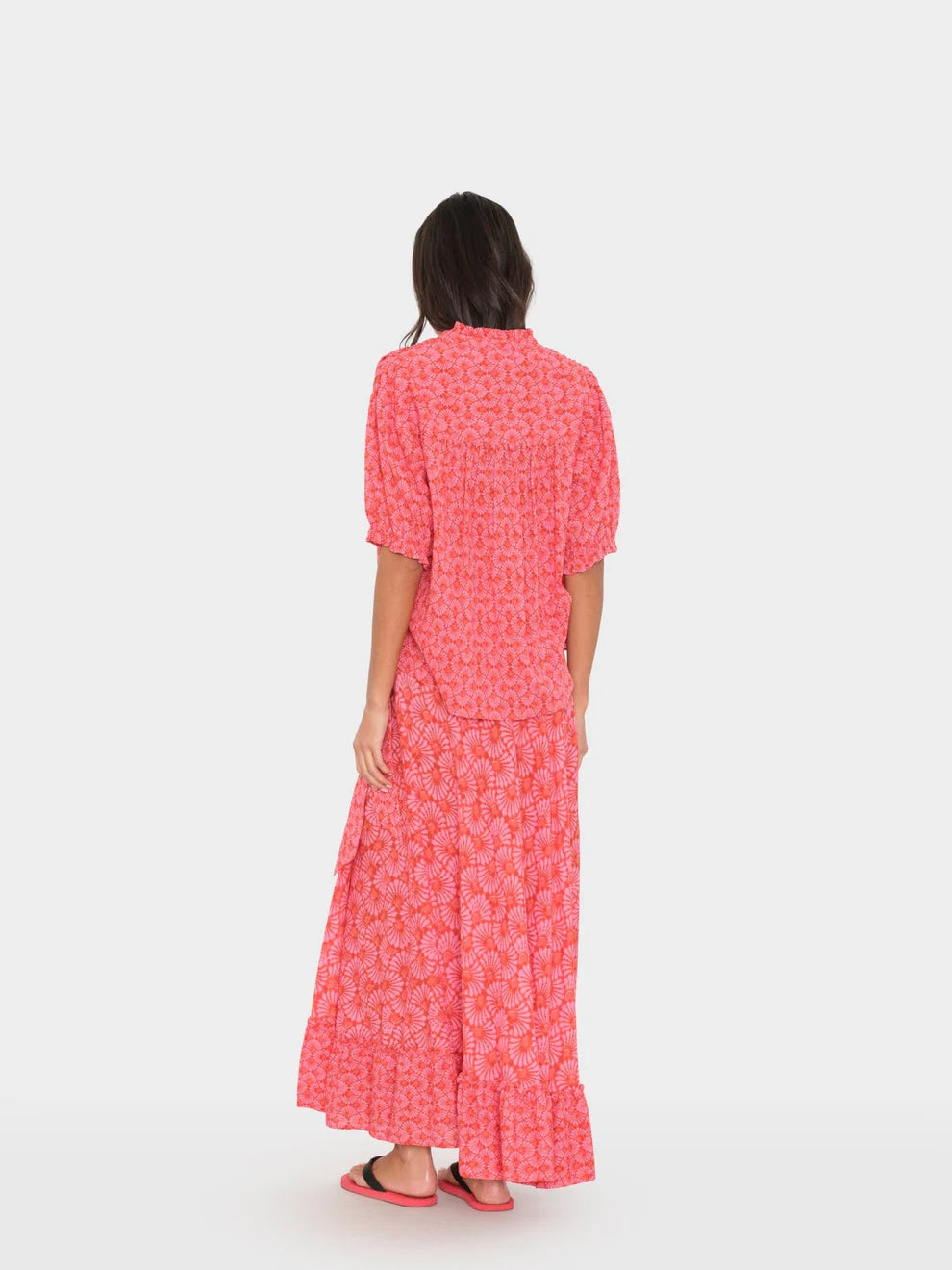 Woman wearing a pink dress with a white pattern on a white background