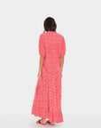 Woman wearing a pink dress with a white pattern on a white background