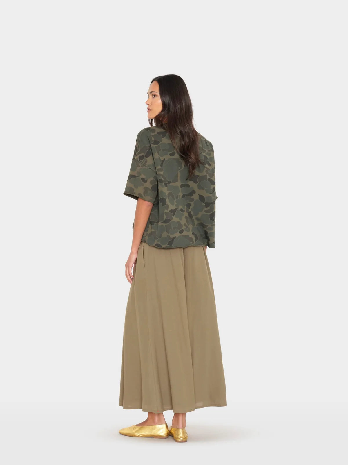 Woman wearing a green camouflage top and beige skirt on a white background