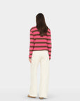 model wearing a pink and brown stripe sweater with wide leg cream sweatpants on a white background , back view