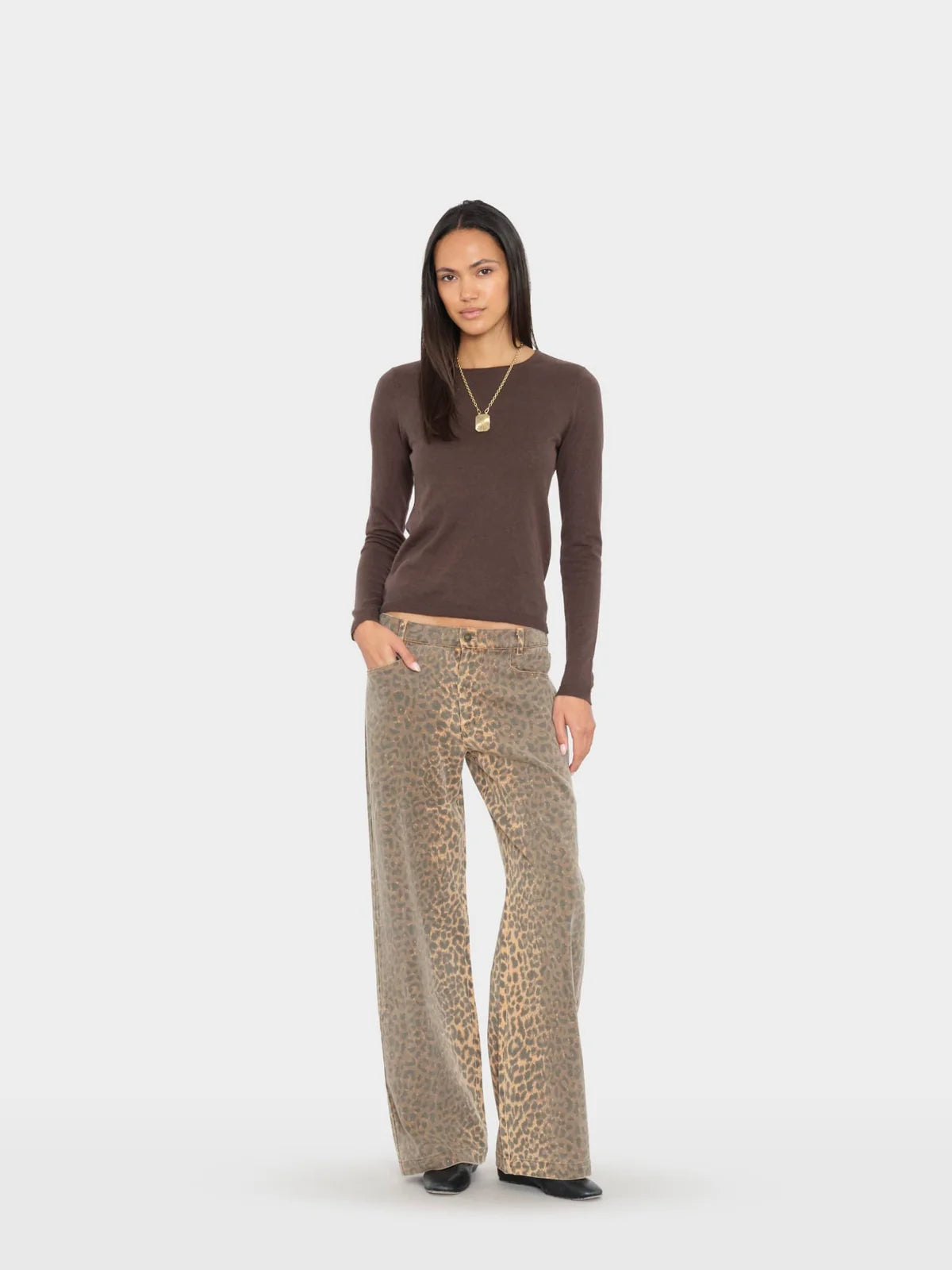 A woman modeling a dark brown long-sleeve knit top and leopard-print wide-leg pants against a light gray studio background.