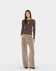 A woman modeling a dark brown long-sleeve knit top and leopard-print wide-leg pants against a light gray studio background.
