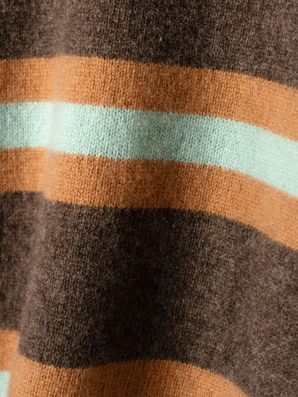 Close-up of a knit fabric with horizontal stripes in dark brown, rust orange, and pale mint green.