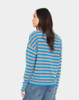 model wearing a tan and blue stripe vneck button down cardigan with blue jeans on a white background, back view
