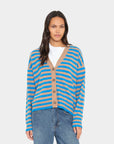 model wearing a tan and blue stripe vneck button down cardigan over a white top with blue jeans on a white background 