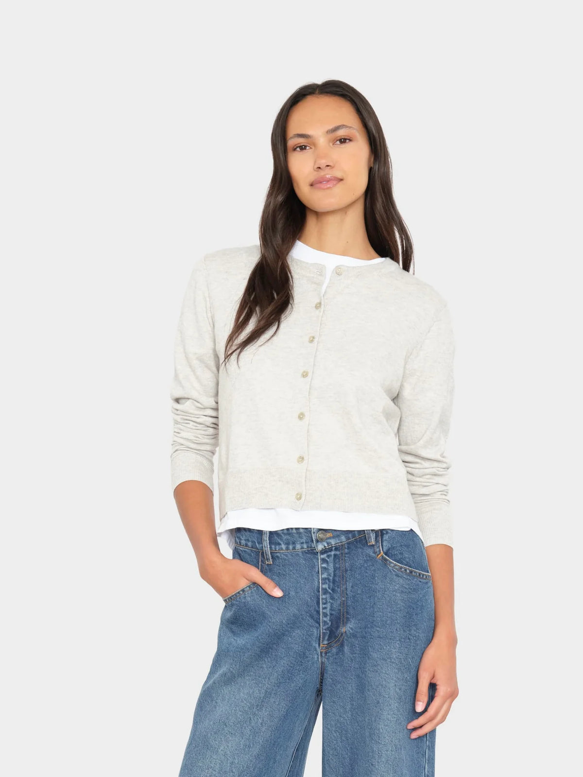 model wearing a grey cardigan over a white top with jeans on a white background 