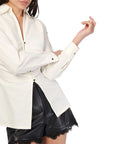 Person wearing a white blouse with black accents on a white background cuff view