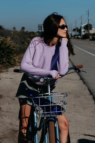 Model on a bike wearing a purple sweatshirt