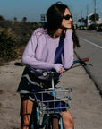 Model on a bike wearing a purple sweatshirt