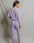 model wearing a purple lounge set on a white background, back view